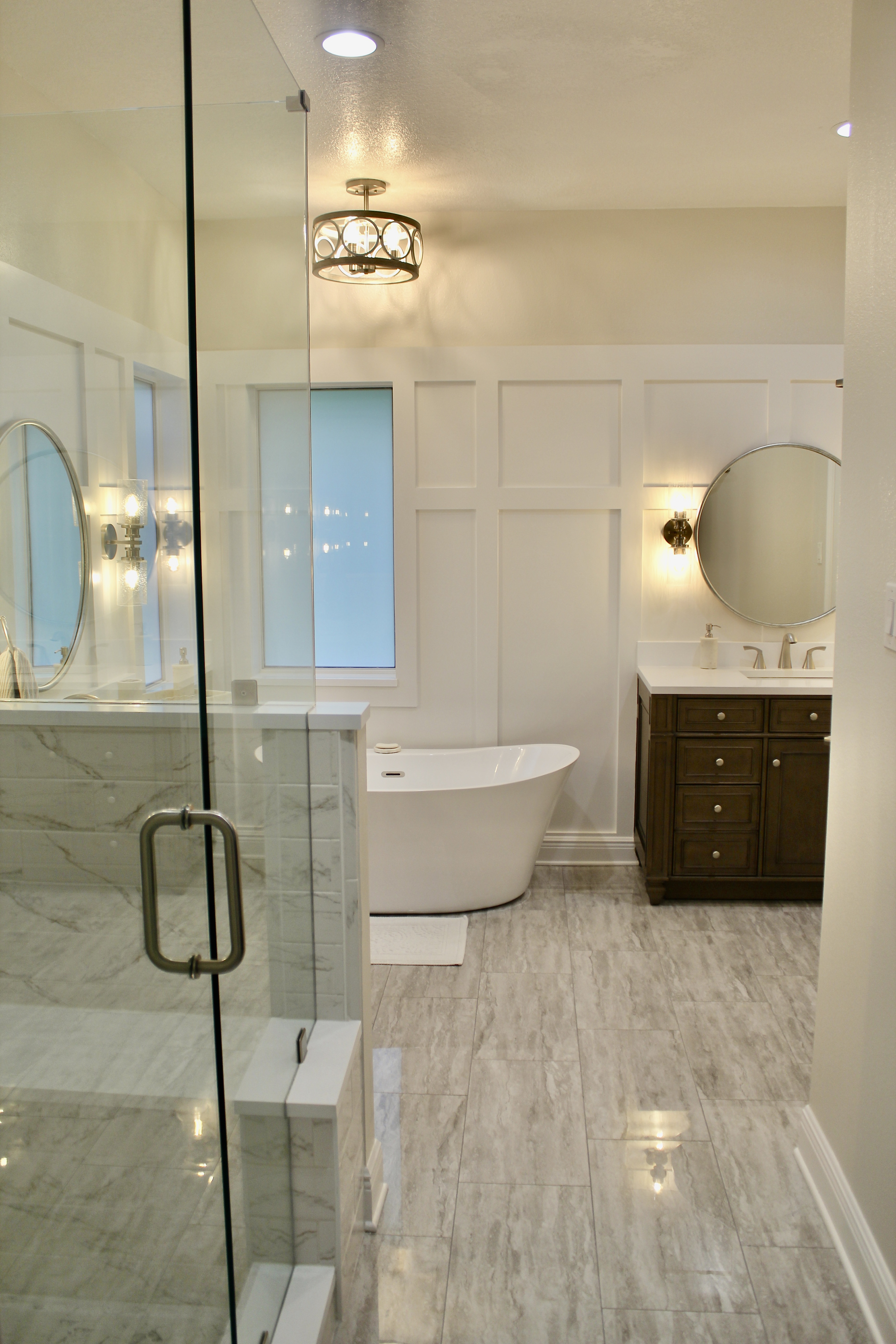 Ocean Springs, MS master bathroom remodel designed by Elizabeth Hall Designs. Bench in shower, freestanding vanities, freestanding bathtub, rustic fixtures