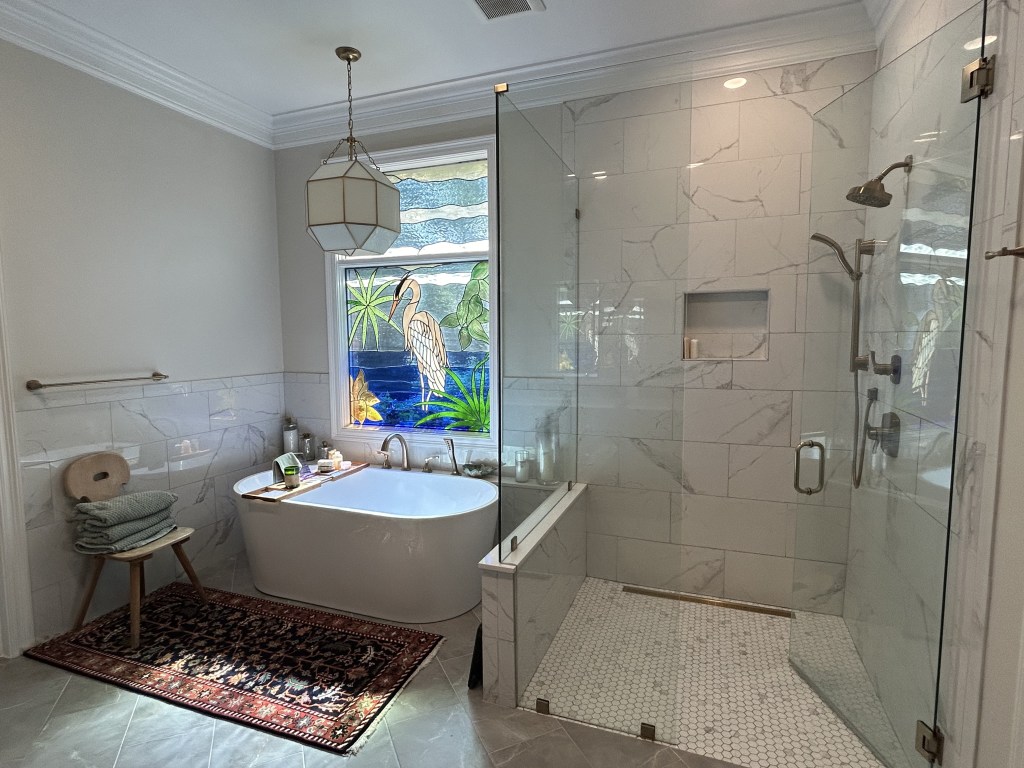 master bathroom renovation with a freestanding bathtub, seamless shower, marble look tile