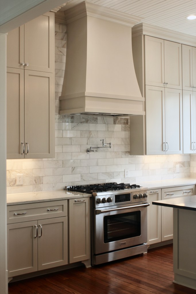Farmhouse kitchen renovation with beige cabinets, wood floors and 12' ceilings.